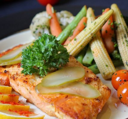 A beautifully plated salmon dish with fresh vegetables and lemon slices, perfect for a gourmet meal.