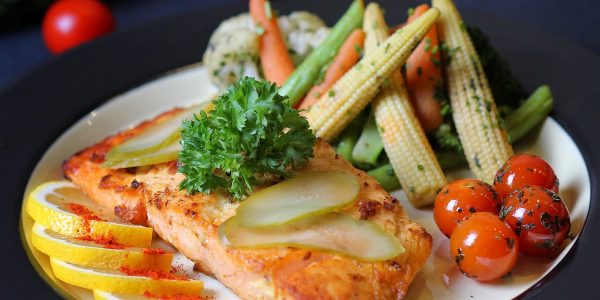 A beautifully plated salmon dish with fresh vegetables and lemon slices, perfect for a gourmet meal.